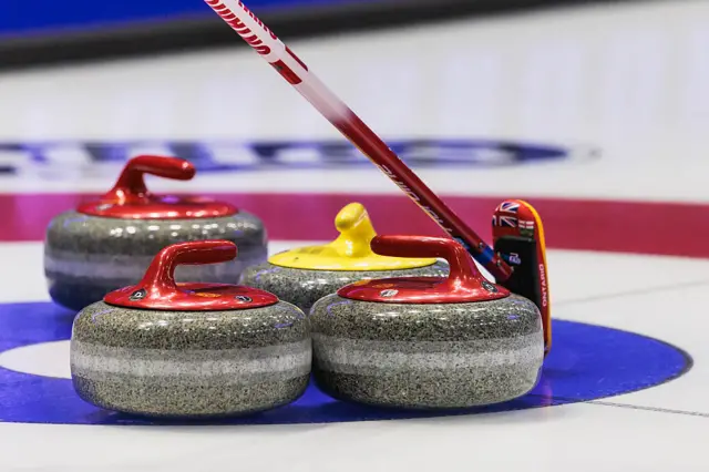 A curling broom and stones