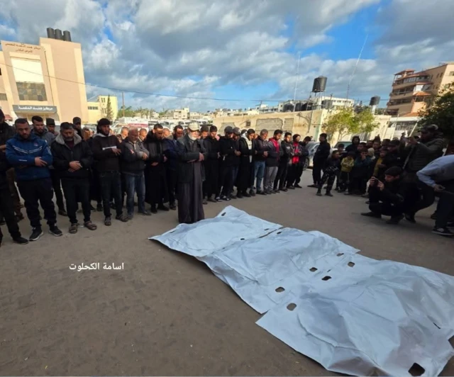 Mourners standing in front of 3 body bags