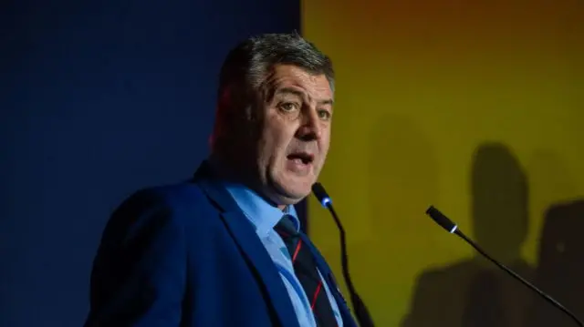 Byrne speaking into a mic