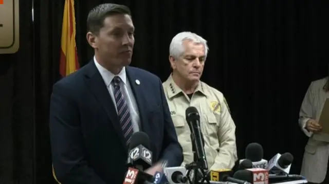 FBI's Heith Janke standing in front of microphones beside Pima County Sheriff Chris Nanos