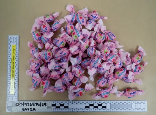 A police image of a pile of pink strawberry-flavoured sweets next to two rulers