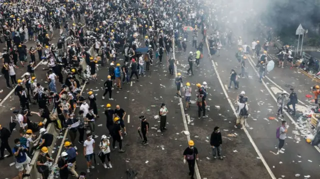Aerial view of a crowded road with protesters wearing black shirts and yellow helmets