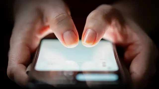 A person using a smartphone with their thumbs