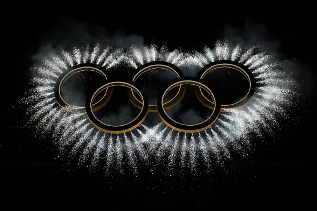 The Olympic rings surrounded by fireworks are displayed