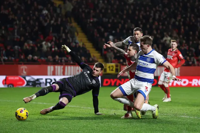 Joe Walsh of Queens Park Rangers makes a save from Lyndon Dykes of Charlton Athletic as Jimmy Dunne looks on