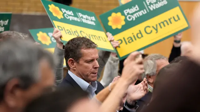 Leader of Plaid Cymru, Rhun ap Iorwerth, surrounded by people holding Plaid Cymru signs