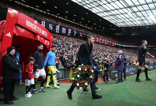 The players and managers come out of the tunnel with wreaths to march the anniversary of the Munich air disaster