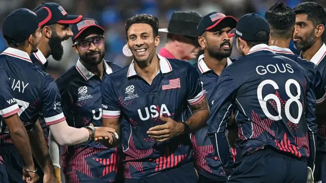 USA's Shadley van Schalkwyk (C) celebrates with teammates after taking the wicket of India's Tilak Varma