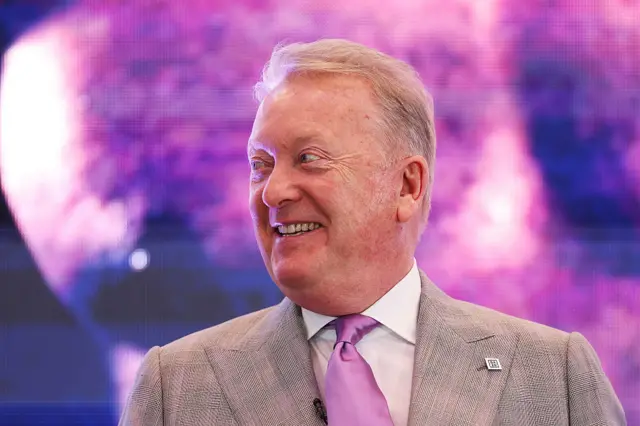 Frank Warren wearing a suit and tie and smiling