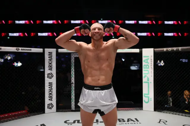 Luke Trainer holds up his arms and stands in the PFL cage