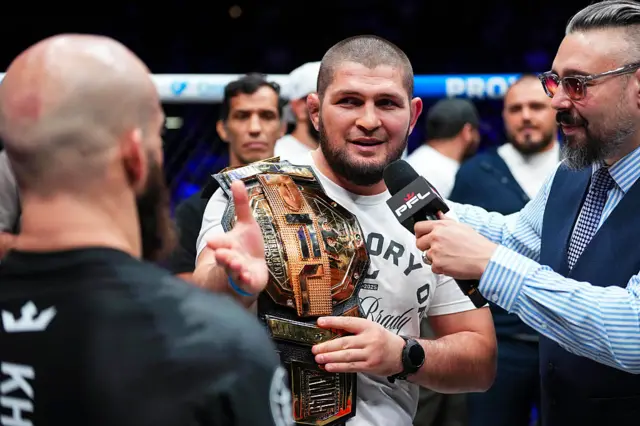 Khabib Nurmagomedov speaks into a microphone and has a PFL belt on his shoulder