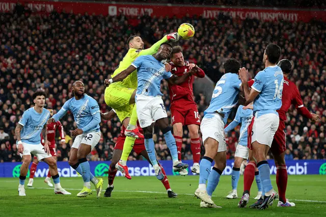 Gianluigi Donnarumma of Manchester City punches the ball over teammate Marc Guehi and Florian Wirtz of Liverpool during the Premier League match between Liverpool and Manchester City at Anfield on February 08, 2026 in Liverpool, England.