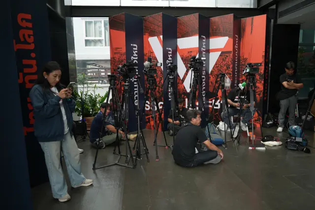 A small gaggle of reporters get into position at the People's Party headquarters in Bangkok
