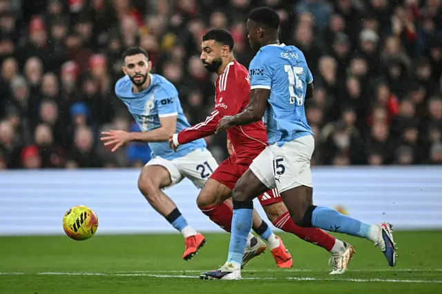 Manchester City's Algerian defender #21 Rayan Ait-Nouri (L) and Manchester City's English defender #15 Marc Guehi (R) challenge Liverpool's Egyptian striker #11 Mohamed Salah (C) during the English Premier League football match between Liverpool and Manchester City at Anfield in Liverpool, north west England on February 8, 2026.