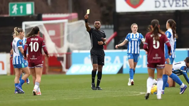 The referee shows Katie Zelem a yellow card
