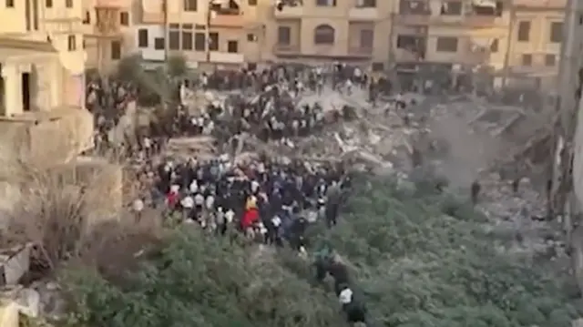 A Screengrab from a video that shows people gathering around rubble and debris after the collapse of two multi-storey buildings in Tripoli, northern Lebanon