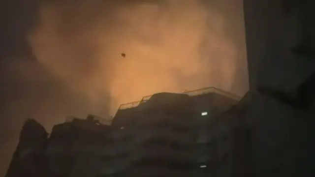 This grab from the video shows what appear to be fires coming from the top of the block illuminating the clouds above