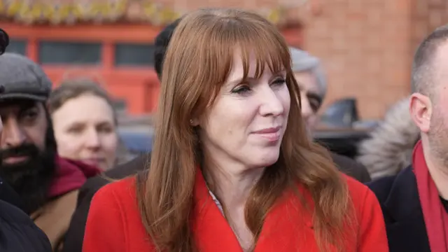 Angela Rayner (red-haired woman in her late 30s) in a bright red jacket surrounded by people outside