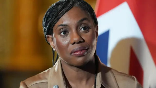 Kemi Badenoch with a UK flag in the background