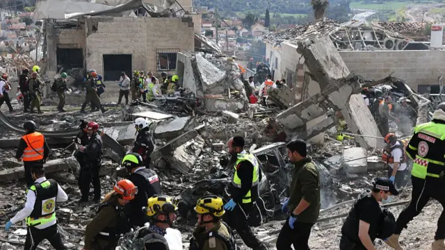 Israeli emergency service officers search the scene of a missile attack near Bet Shemesh