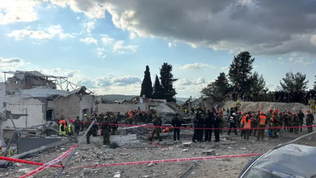 A group of emergency service workers and caution tape barriers near a damaged building in Beit Shemesh.