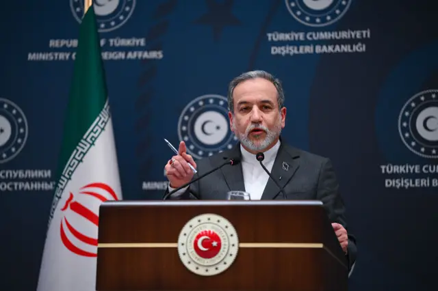 Abbas Araghchi, in a suit, speaking behind a pdoium.