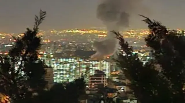 Smoke rising over the city lights of Tehran