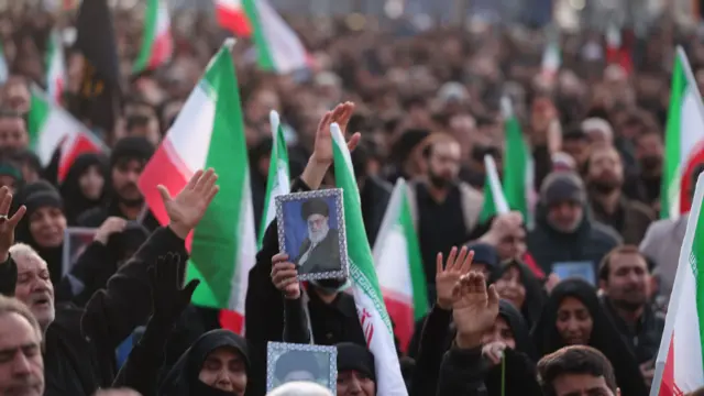 Iranians wearing black and waving the flag in Tehran mourning the death of Ayatollah Ali Khamenei