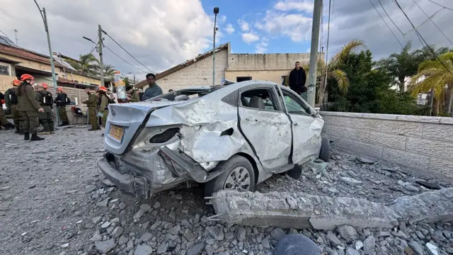 A dented and damaged car surrounded by rubble in Beit Shemesh following an Iranian strike.