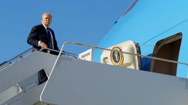 Donald Trump stands at the top of some aircraft steps about to board Air Force One