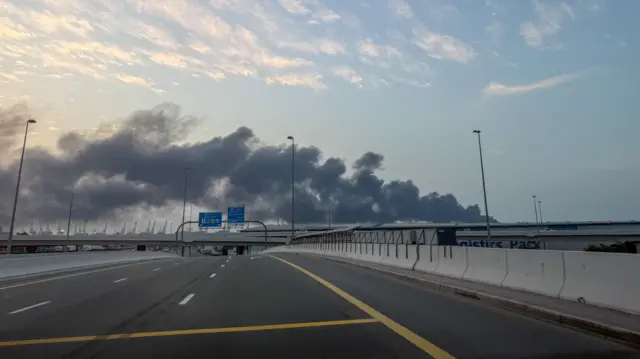 Dark grey smoke billows into the sky following a strike Jebel Ali port