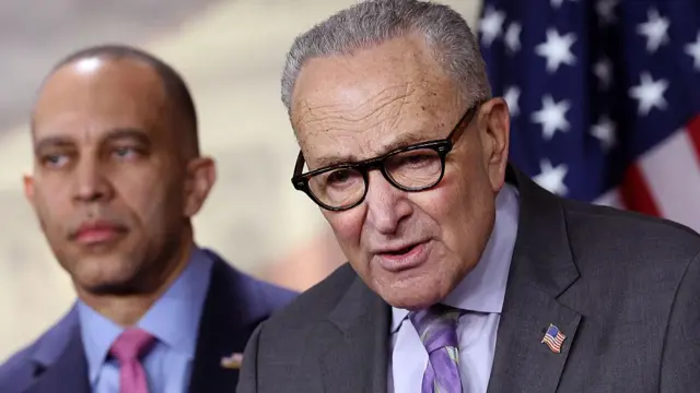 Hakeem Jeffries (left) and Chuck Schumer stand in front of an American flag as Schumer speaks