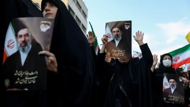 People hold pictures of Supreme Leader Mojtaba Khamenei at a public gathering in Iran.