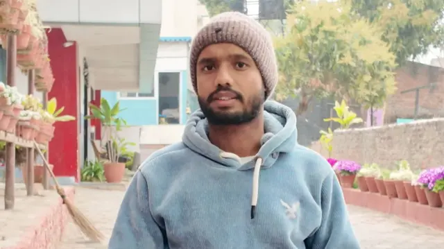 Rakesh Mahto wears a white beanie and light blue hoodie