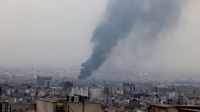 Smoke rises in between tower blocks in Tehran. A number of tower blocks can be seen in the front of the photo