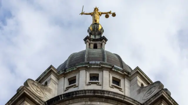 A gold statue of Lady Justice sits on top of the main dome of the Old Bailey building in London
