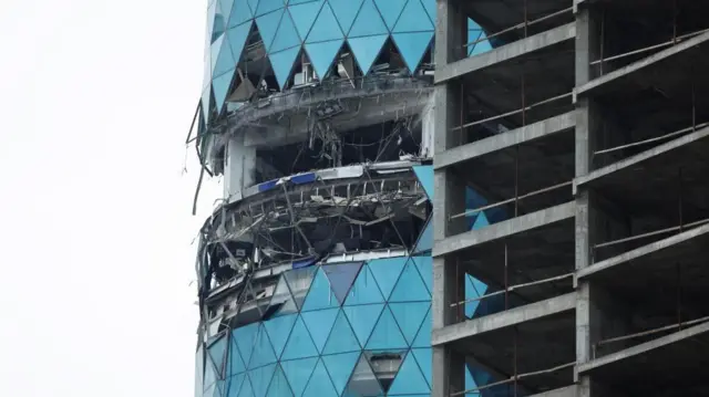 Several floors of a bright blue glass building are smashed and shattered following a strike