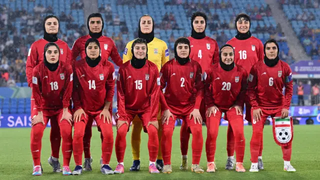 A team photo of the Iranian women's football team wearing red jerseys