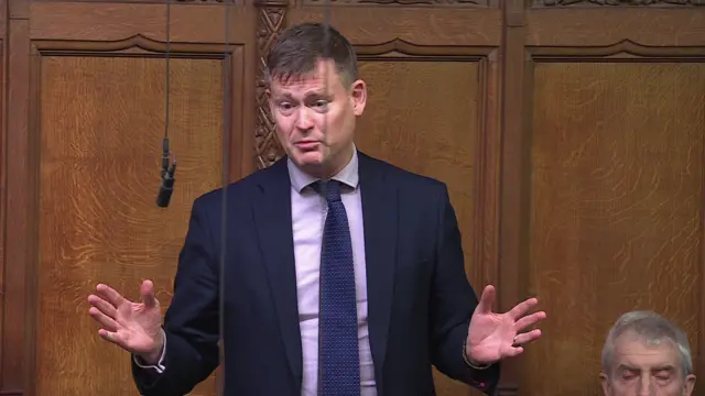 Labour MP Justin Madders addressing House of Commons with both hands either side with palms facing outwards and with a microphone hanging in front of him