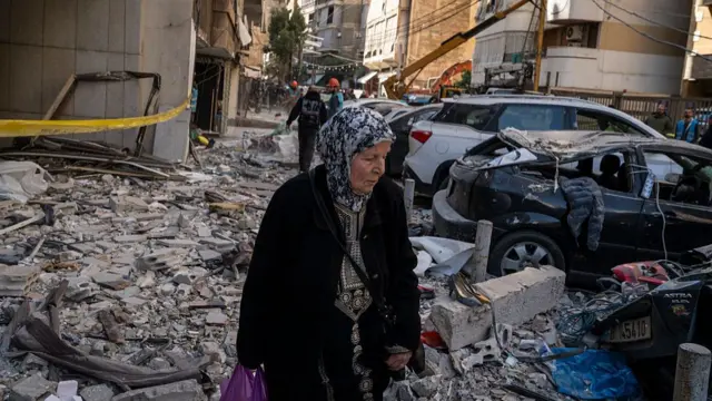 elderly woman walking through rubble of destroyed building