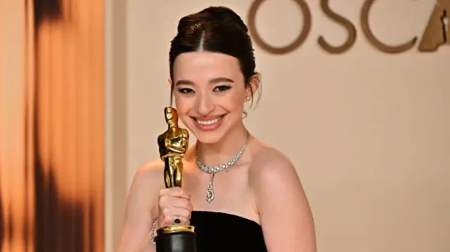 Mikey Madison in a black gown holding her Oscar