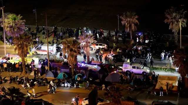 Cars, vans and people are seen on a busy street in Beirut at night.