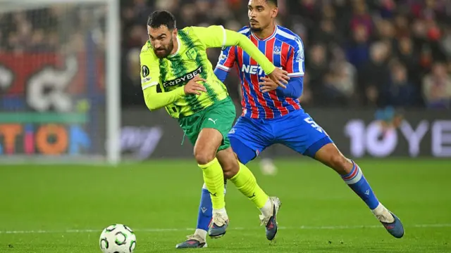 iad Bajic of AEK Larnaca is challenged by Maxence Lacroix of Crystal Palace d