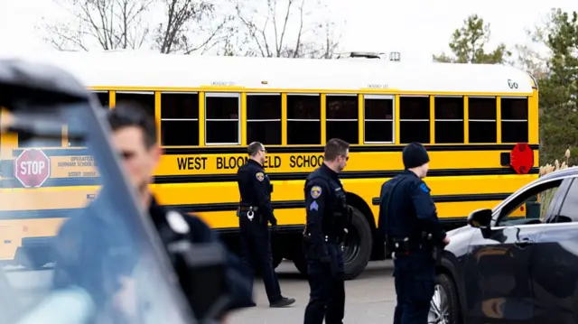 police officers standing in front of a school bus