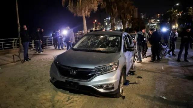 People gather at the site of a drone strike targeting a car in Ramlet al-Baida at Corniche Beirut