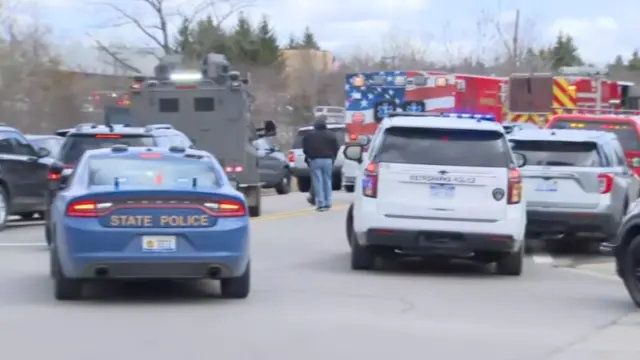 police cars, an ambulance, a fire truck, and an armored vehicle parked at the scene