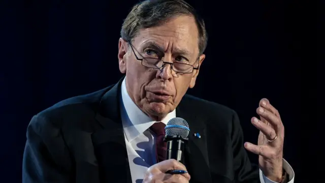 David Petraeus wears a suit speaking at a microphone