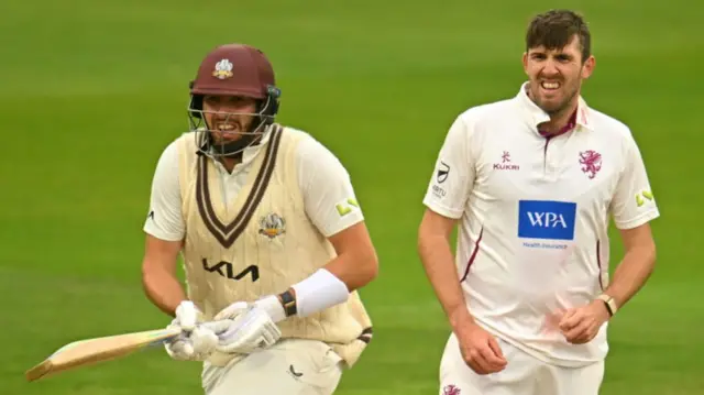 : Jamie Overton of Surrey runs between the wickets as Brother Craig Overton of Somerset looks on