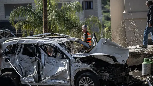A burnt out car is seen in the town