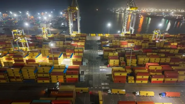 Yellow and red shipping containers piled how in a port